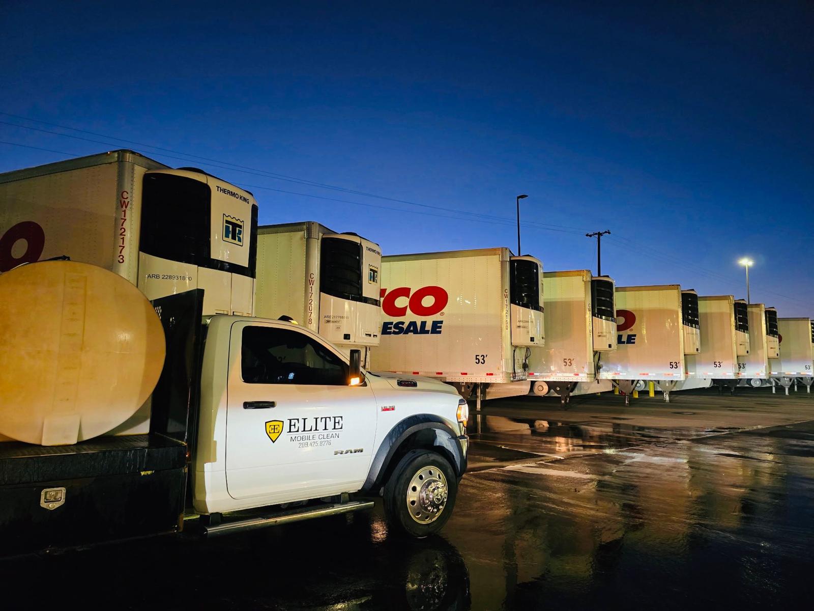 Elite Mobile Clean truck beside a row of washed Costco trailers at dusk